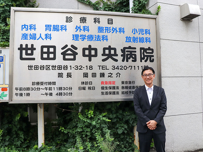 インタビュイー徳保様と病院看板