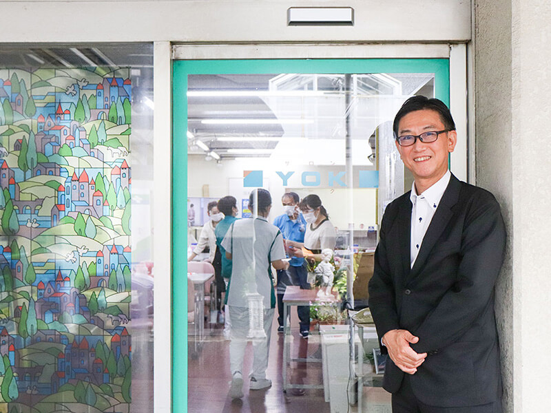 インタビュイー徳保様と施設内食堂入り口